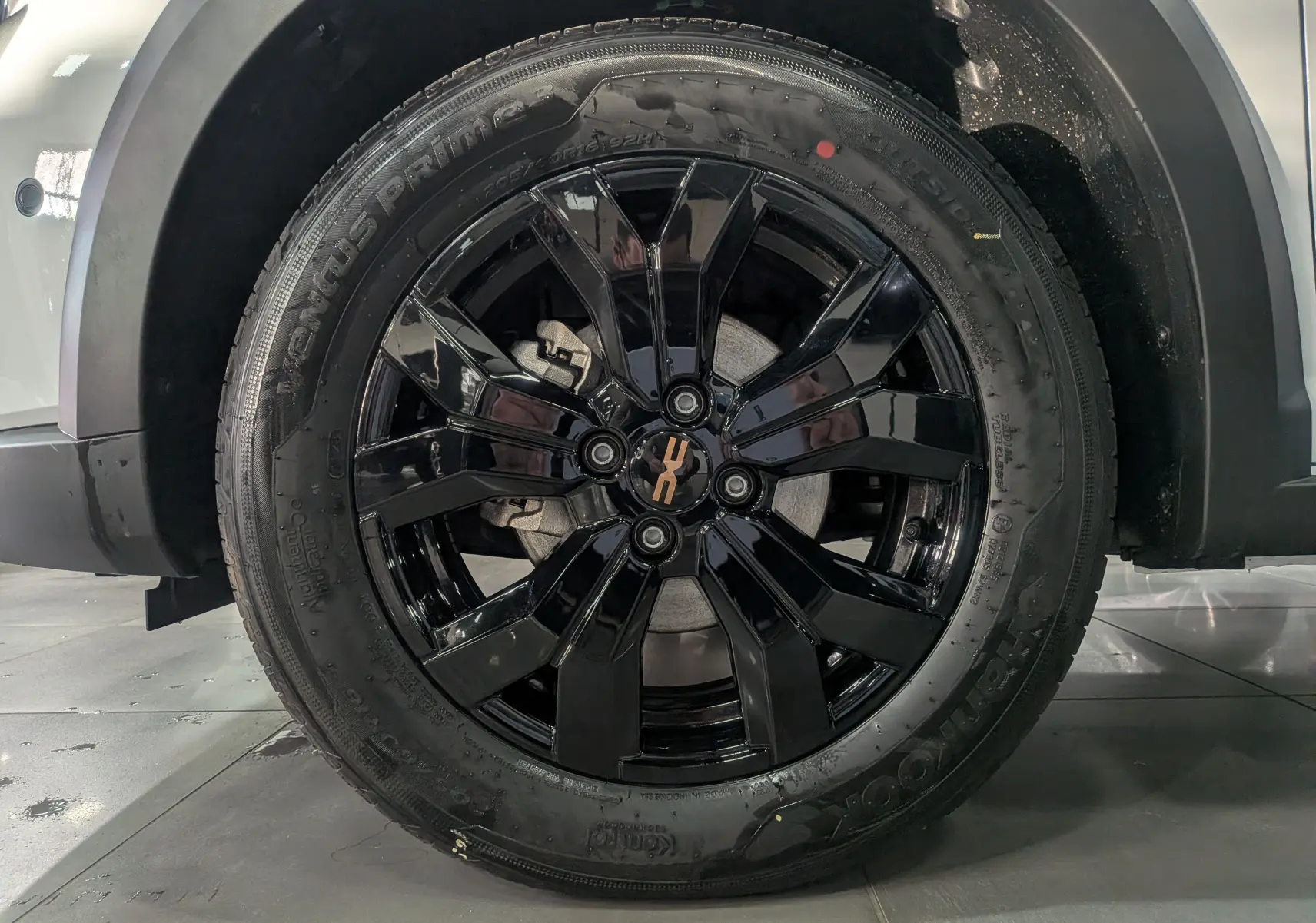 Gros plan sur la roue avant gauche de la Dacia Sandero Stepway blanche avec jante noire brillante et logo central doré.