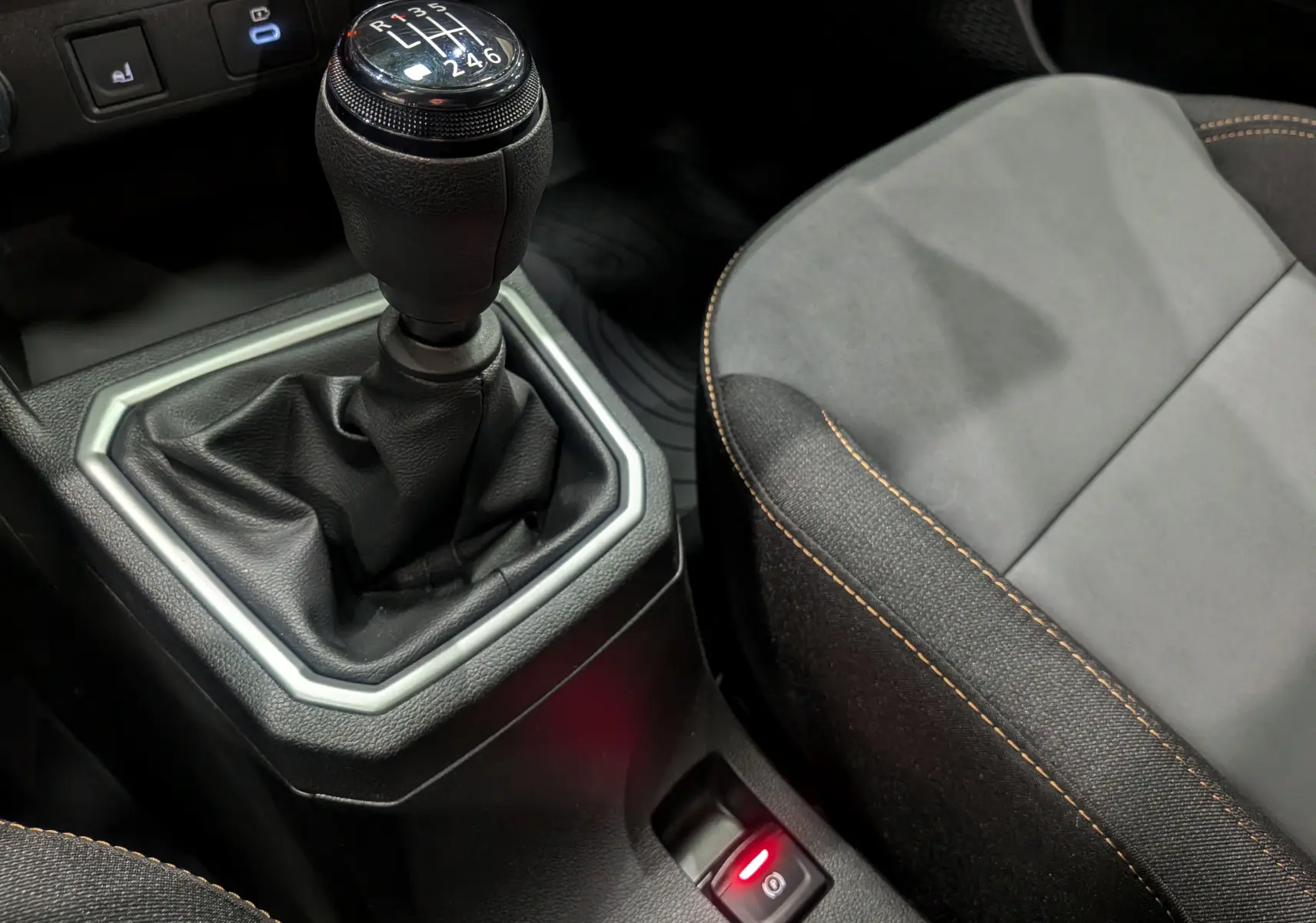 Le levier de vitesse manuel de la Dacia Sandero Stepway TCe 110, entouré de garnitures noires et tissu gris avec surpiqûres orange.