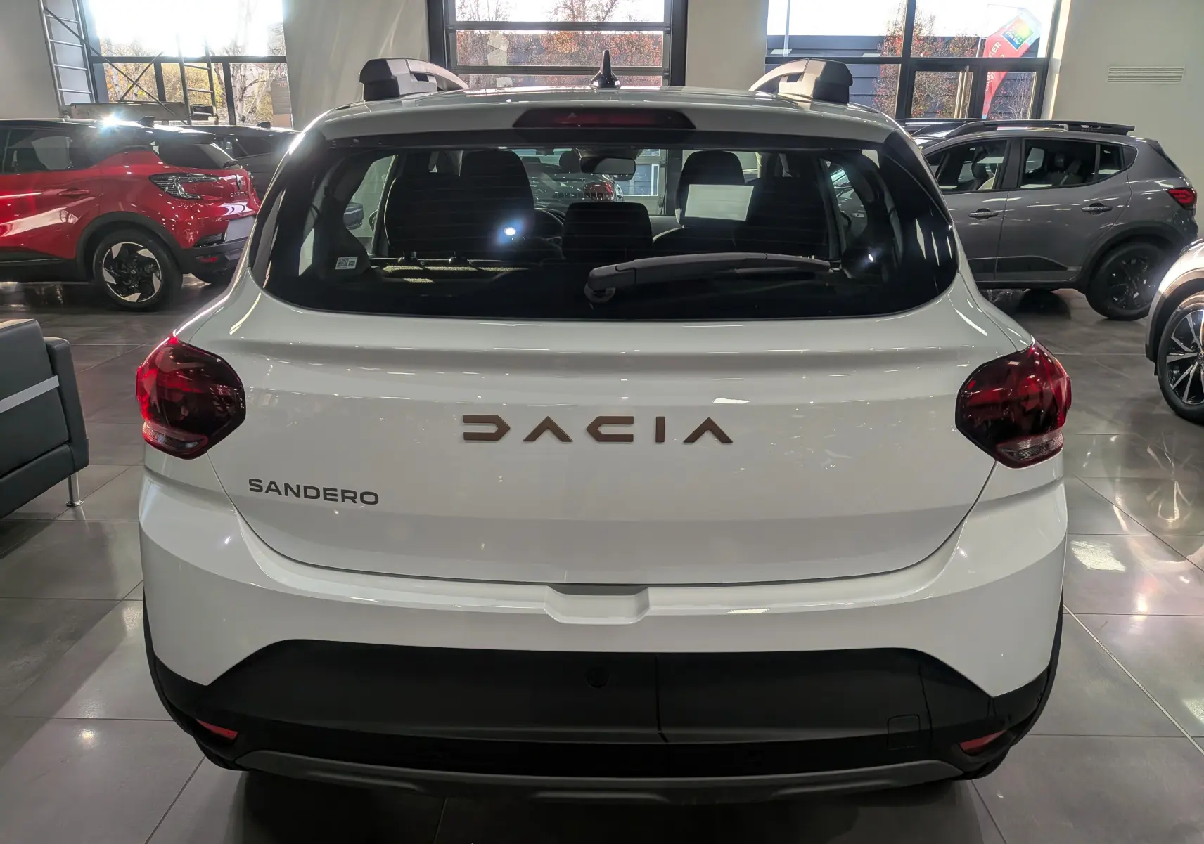Vue arrière d'une Dacia Sandero Stepway blanche Glacier 2025, avec feux arrière rouges et logo DACIA en relief.
