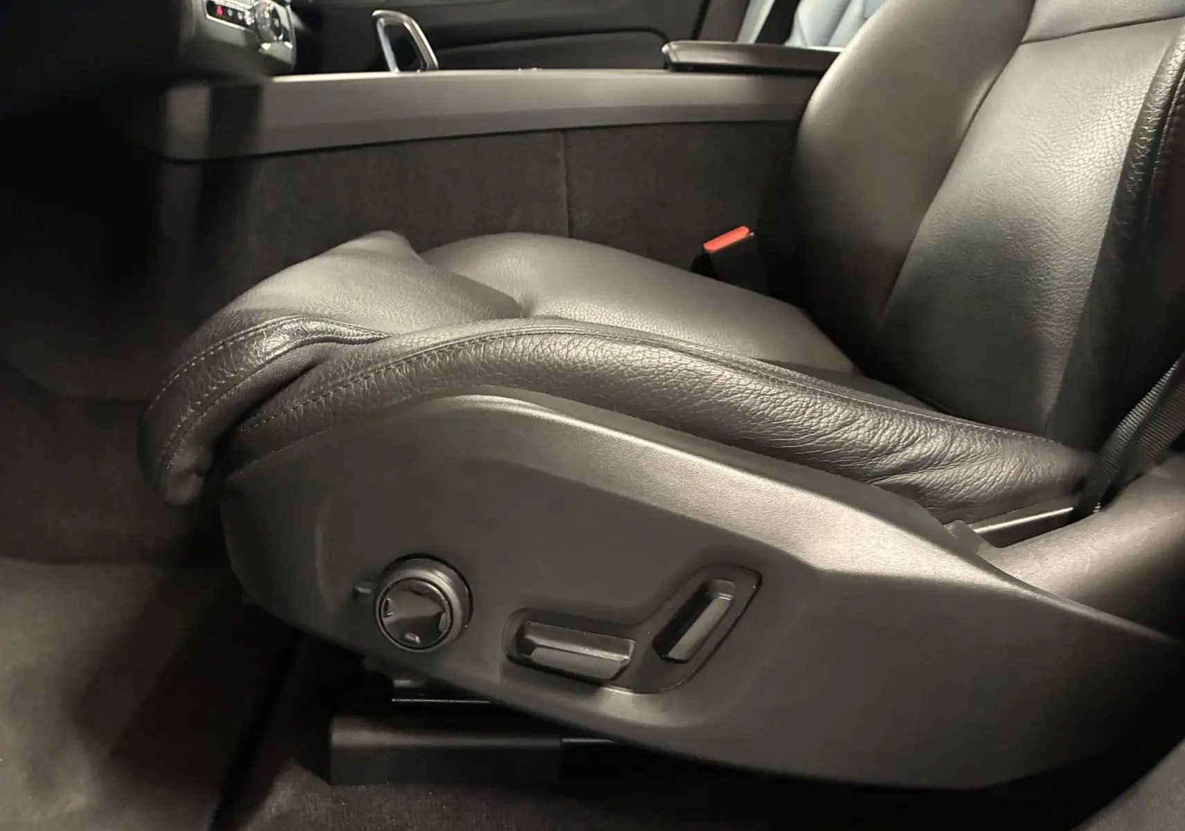 Gros plan sur le siège conducteur en cuir noir avec commandes électriques du Volvo XC60 2023, intérieur sombre.