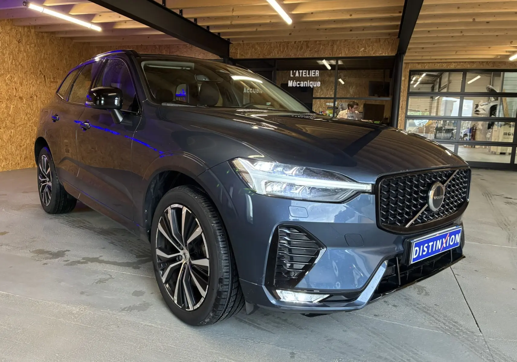 Volvo XC60 bleu vue 3/4 avant droit, calandre noire laquée et jantes alliage 20 pouces en Y noir/diamant.