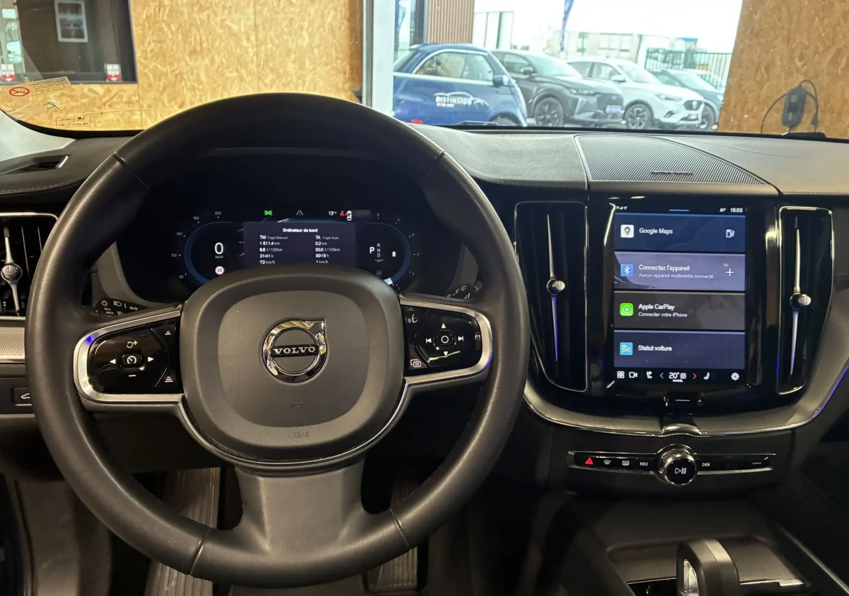 Vue intérieure centrée sur le volant et la console tactile du Volvo XC60 2023, ambiance noire élégante.