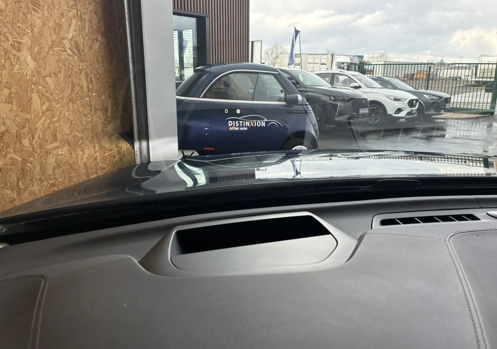 Vue depuis l'intérieur vers l'avant, montrant une Volvo XC60 bleue garée à l'extérieur derrière une vitre.