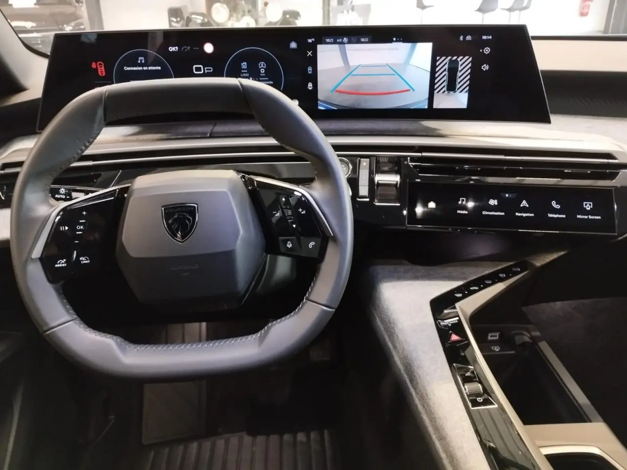 Vue intérieure centrée sur le volant et le tableau de bord avec écran incurvé du Peugeot 3008 gris Artense 2024.