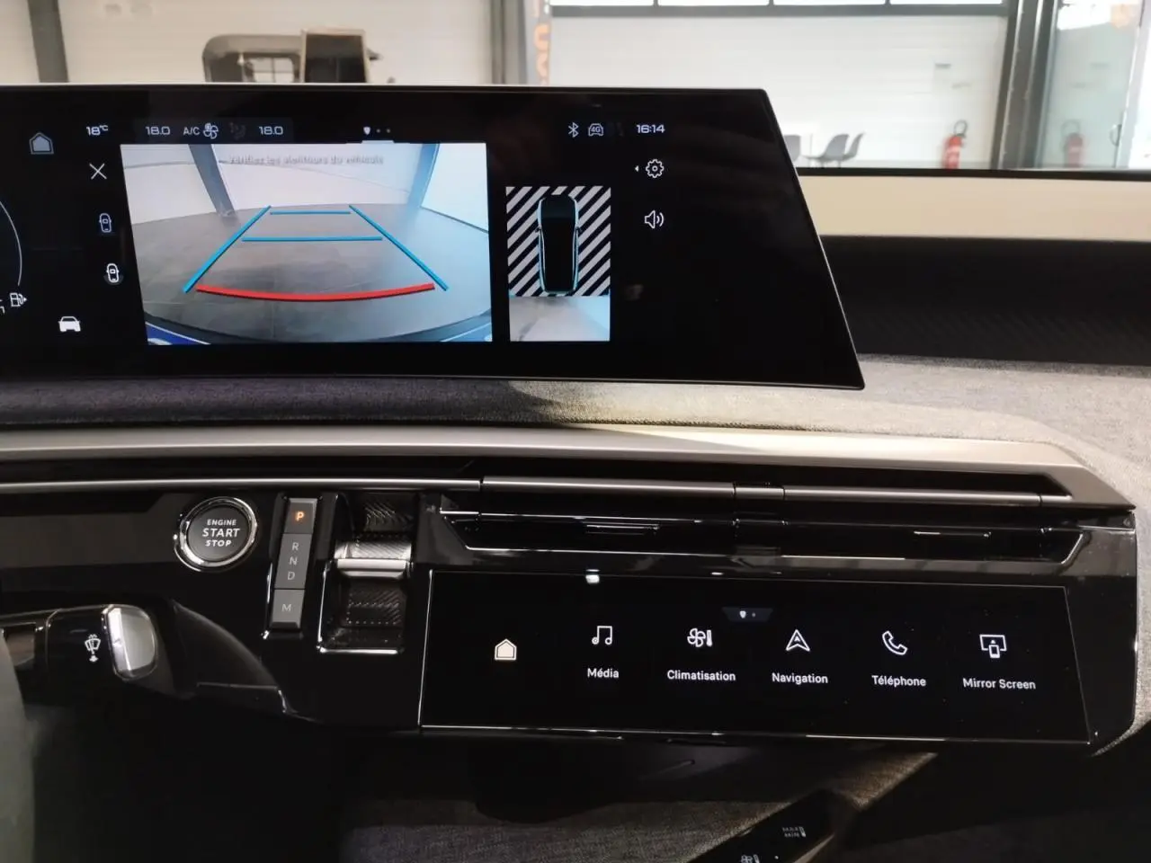 Vue rapprochée de la console centrale et écran incurvé du Peugeot 3008 gris Artense 2024 avec affichage caméra de recul.