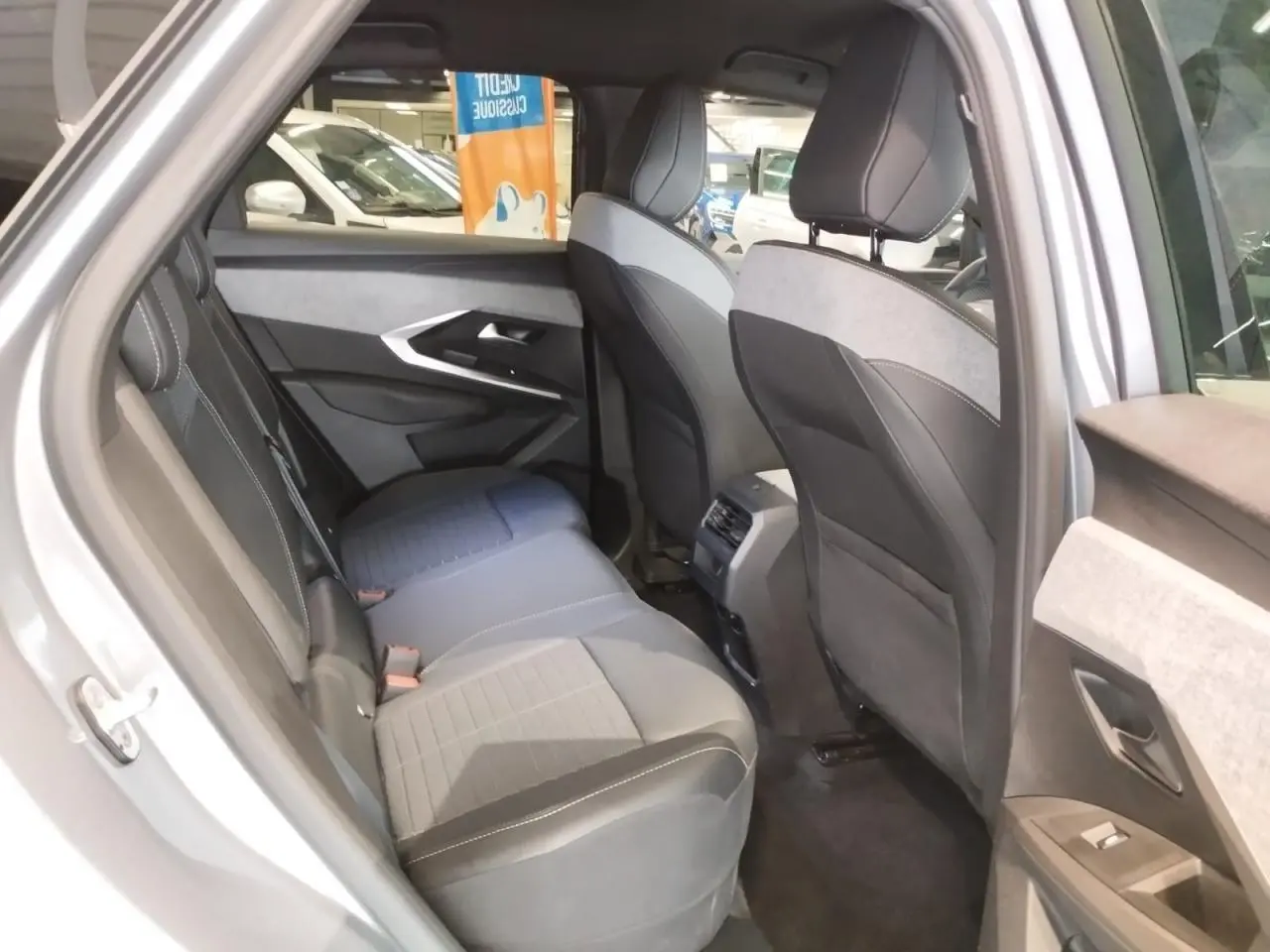 Vue intérieure côté gauche des sièges arrière en tissu gris et noir du Peugeot 3008 2024 hybride, avec port USB central visible.
