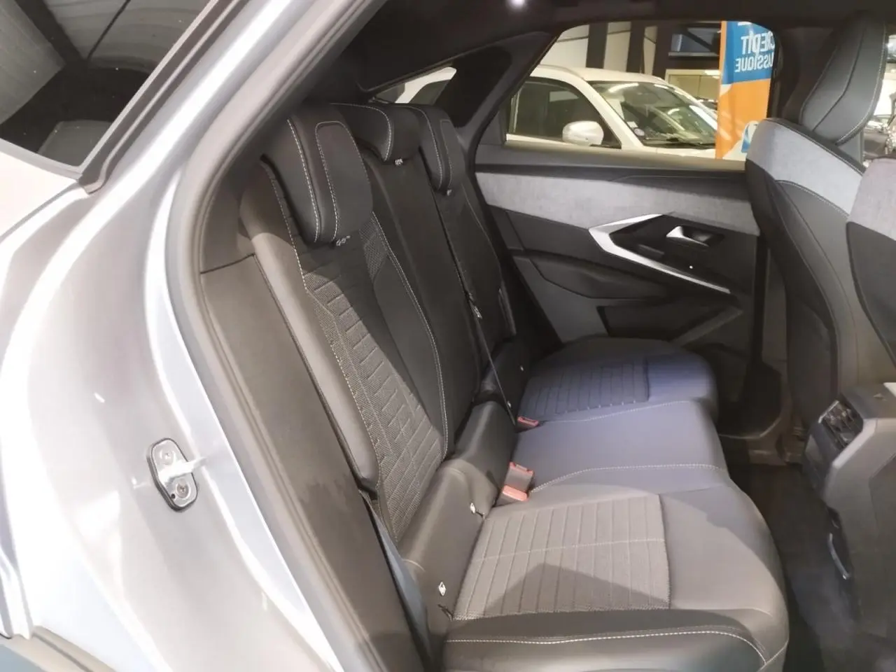 Vue intérieure côté gauche des sièges arrière en tissu et cuir noir du Peugeot 3008 gris Artense, avec détails de la porte et console centrale.