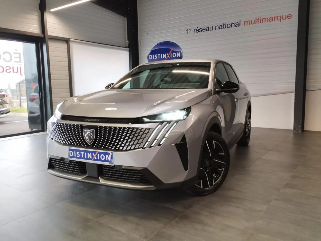 Peugeot 3008 gris Artense vue 3/4 avant en intérieur avec calandre distinctive et feux LED allumés.