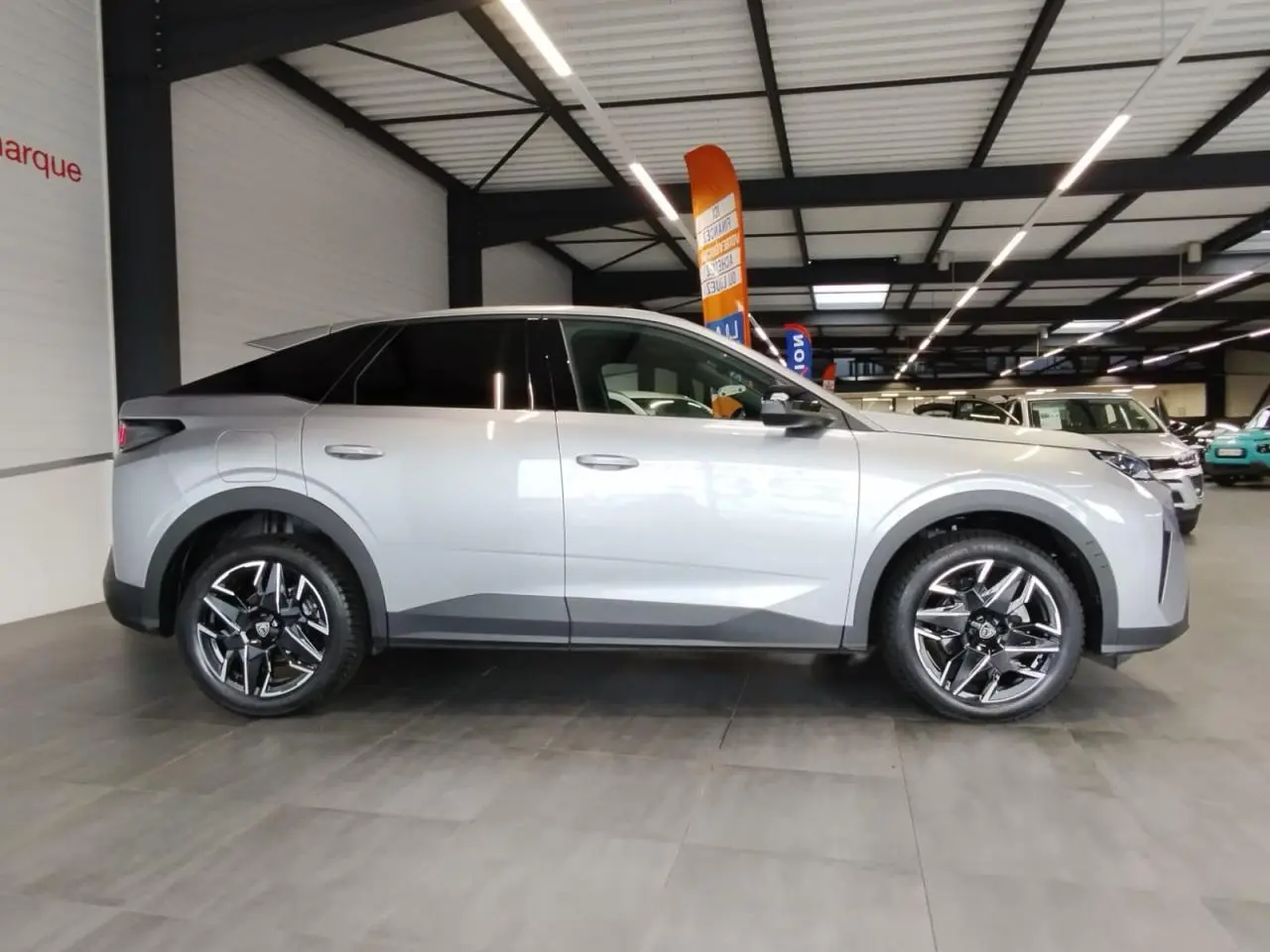 Vue de profil côté gauche du Peugeot 3008 gris Artense avec jantes alliage noires et toit noir en concession.