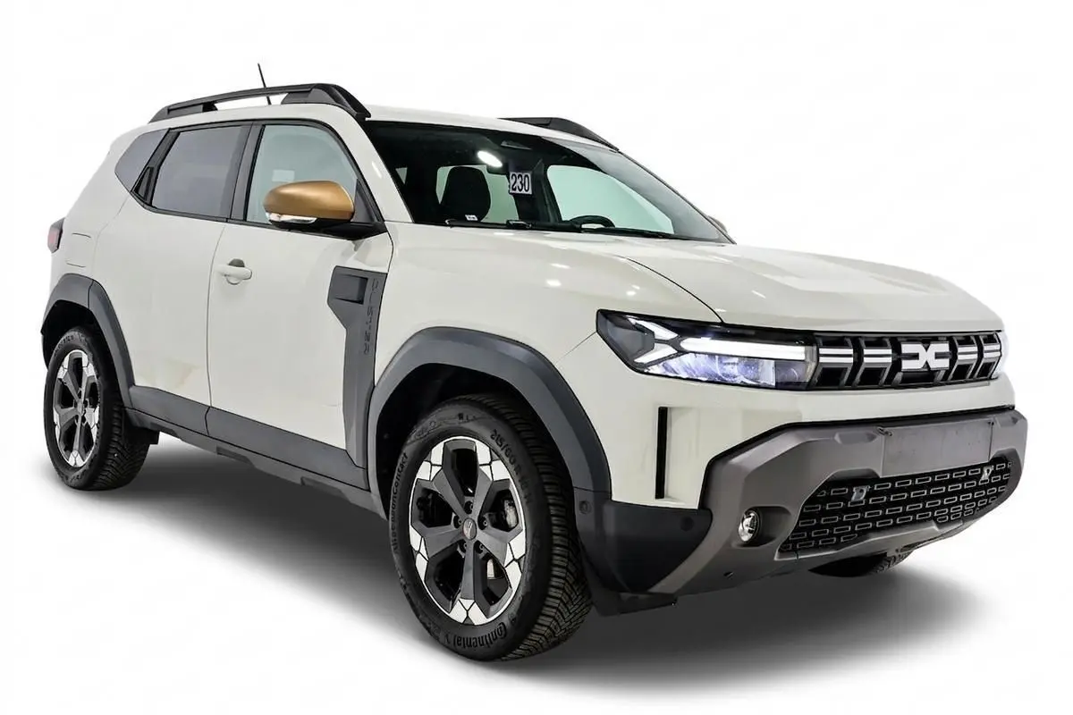 Vue 3/4 avant droite du Dacia Duster 2024 couleur Sandstone avec rétroviseur doré et jantes bi-ton.