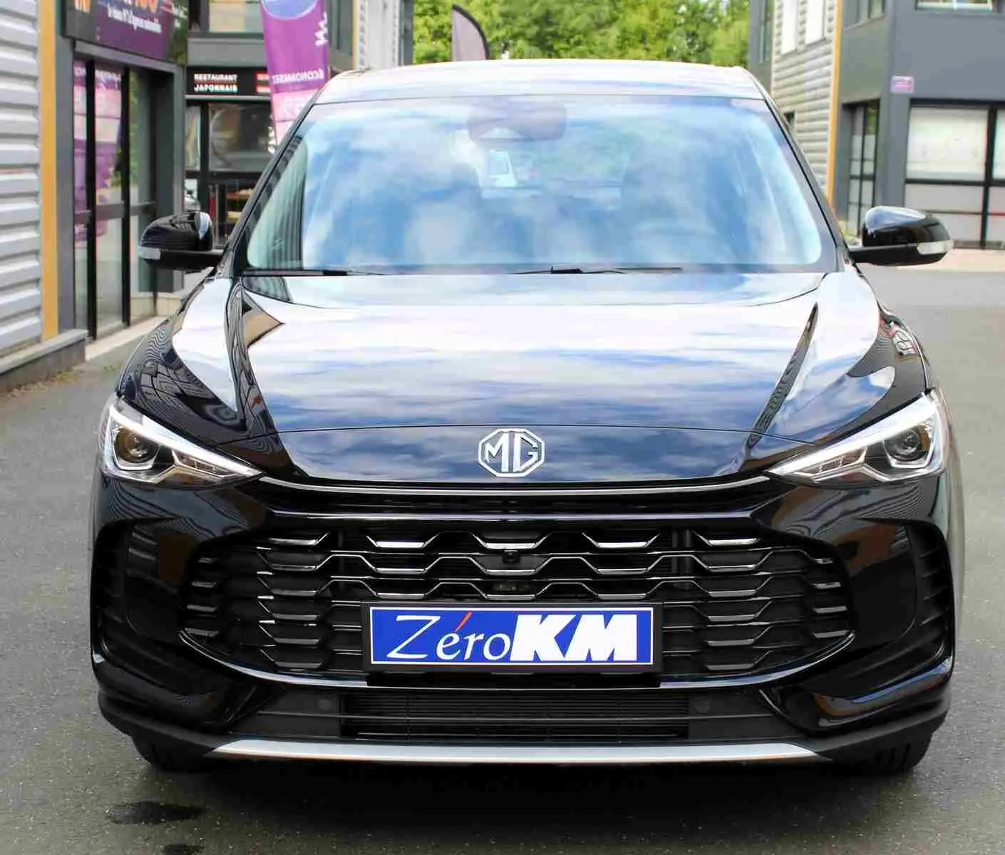Vue intérieure côté conducteur du MG ZS 1.5L HYBRID+ 2026 en Pebble Black Metal, sièges tissu gris et noir, volant cuir multifonction.