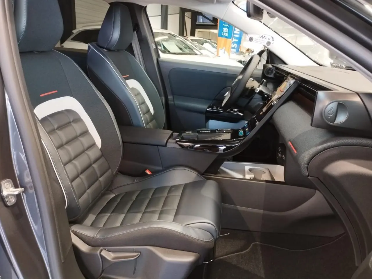 Vue intérieure côté conducteur du Citroën C5 Aircross gris platine, sièges cuir et tissu bleu avec console centrale noire brillante.