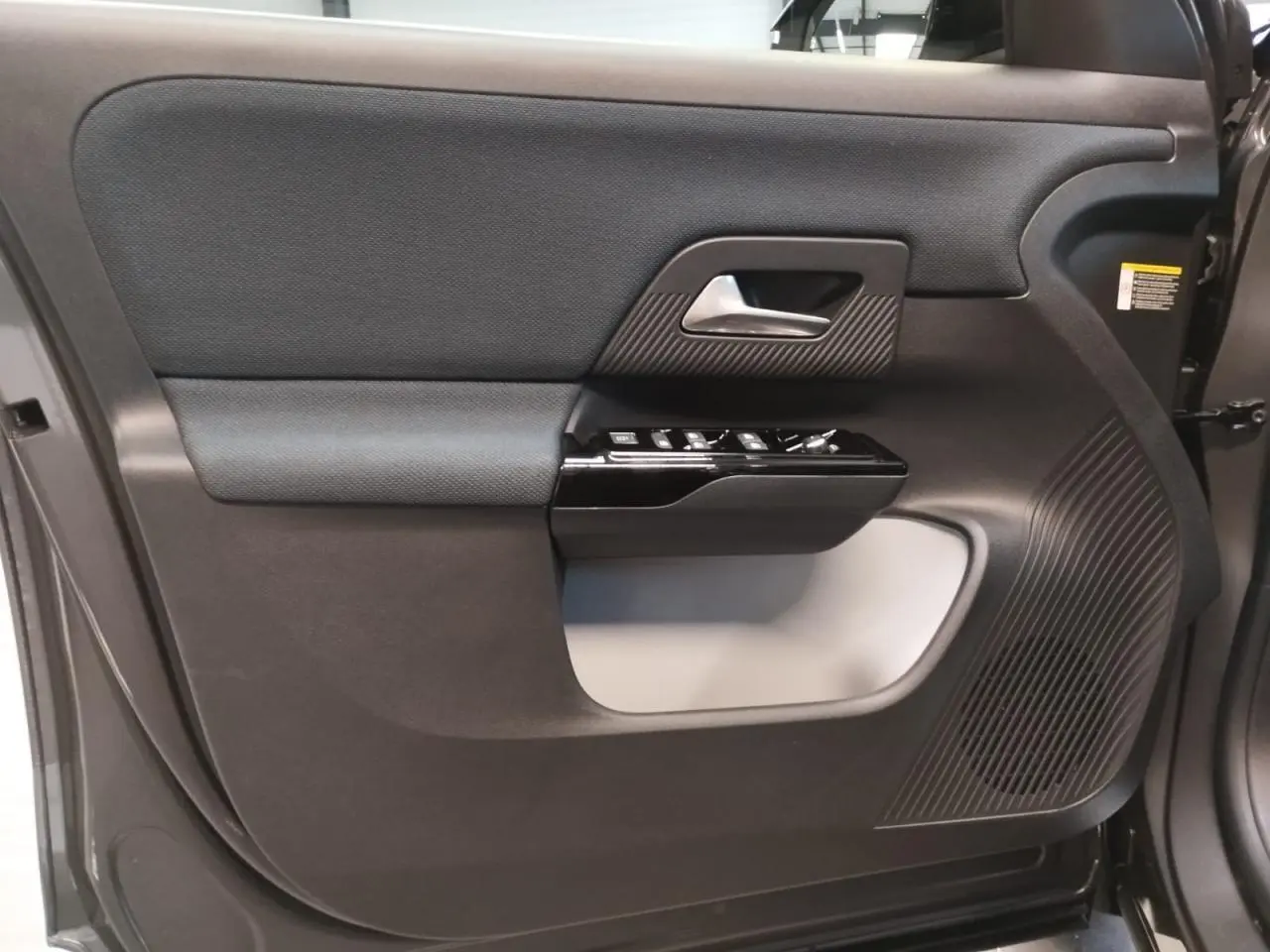 Vue intérieure côté gauche de la porte avant gris platine du Citroën C5 Aircross avec commandes et haut-parleur intégrés.