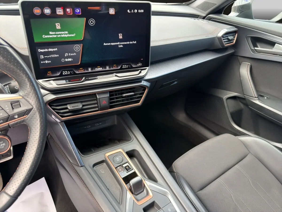 Intérieur noir du CUPRA Formentor 2025 vu côté passager, avec écran tactile central et volant cuir perforé.