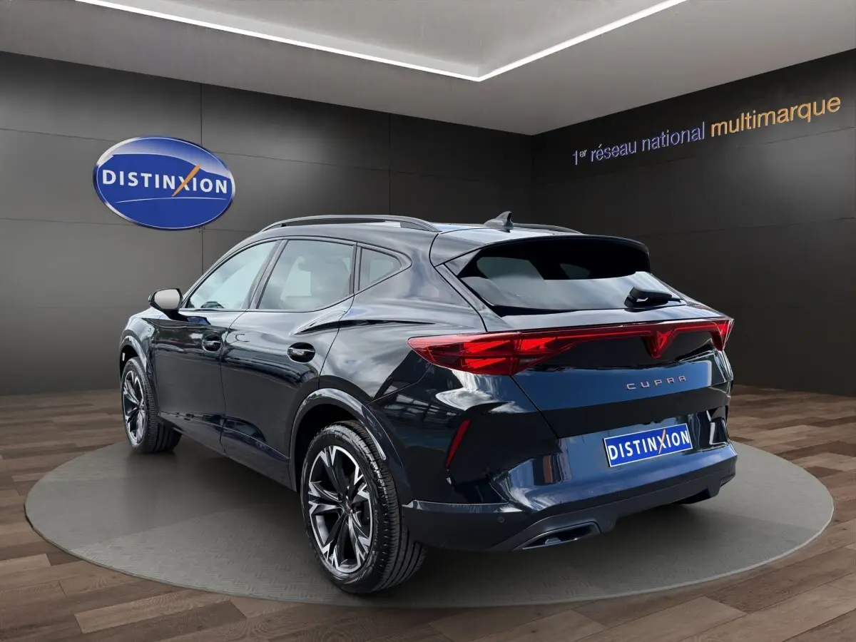 Vue 3/4 arrière droite d'un CUPRA Formentor bleu foncé avec feux arrière LED et jantes noires en alliage.
