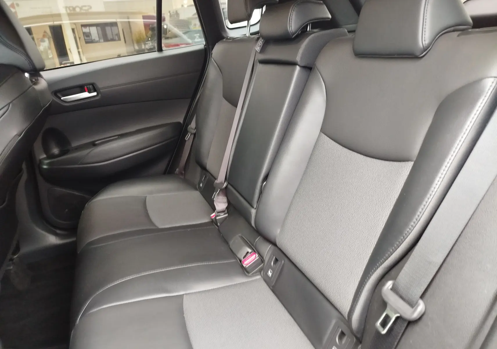 Vue intérieure côté droit des sièges arrière en cuir noir et tissu gris du Toyota Corolla Cross Hybrid 140 Luxury Limited 2025.