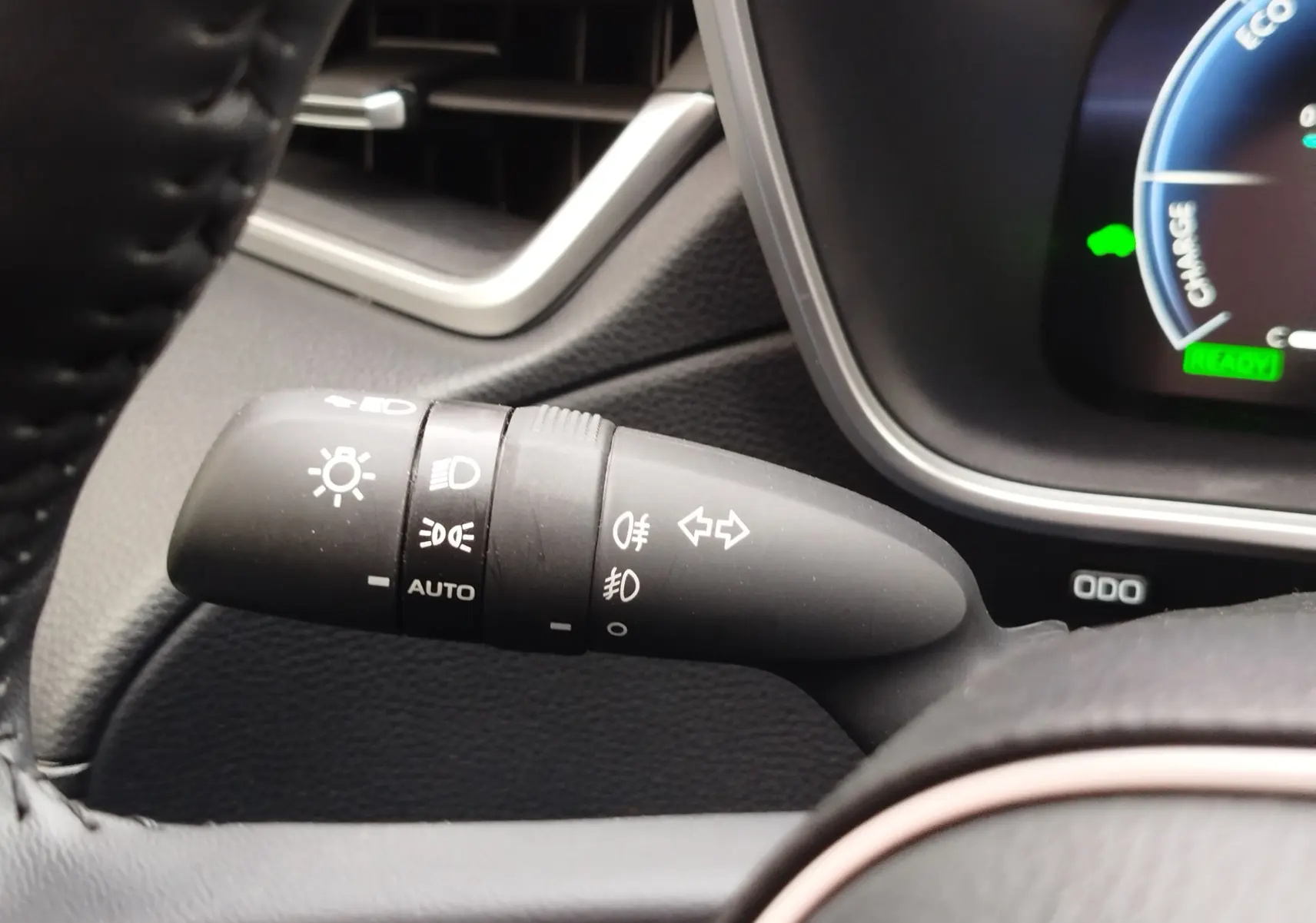 Gros plan sur la commande des feux et clignotants dans l’habitacle noir du Toyota Corolla Cross Hybrid 140 Luxury Limited 2025.