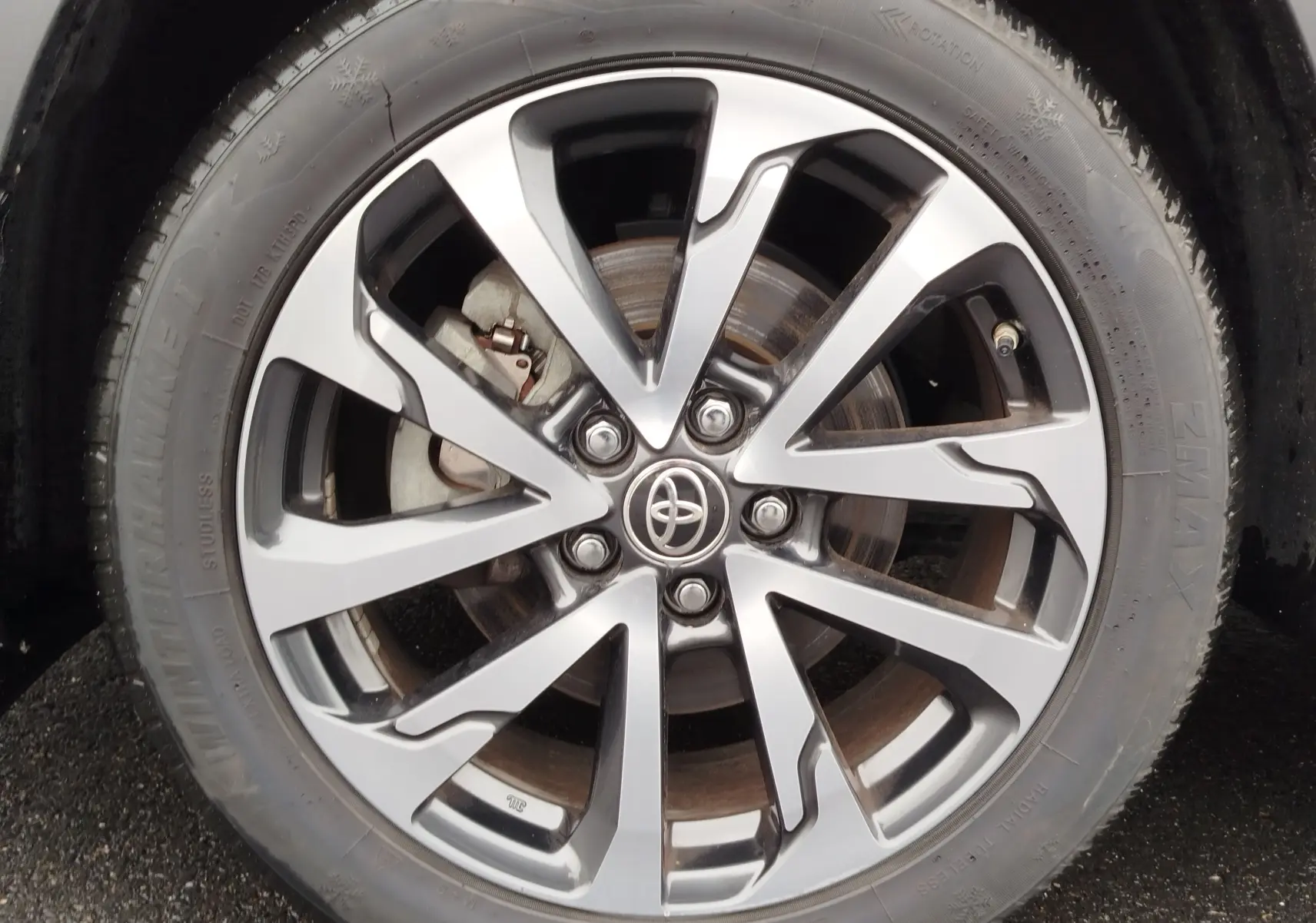Gros plan sur la jante alliage bicolore et le pneu d'une Toyota Corolla Cross Hybrid 140 Luxury Limited noire.