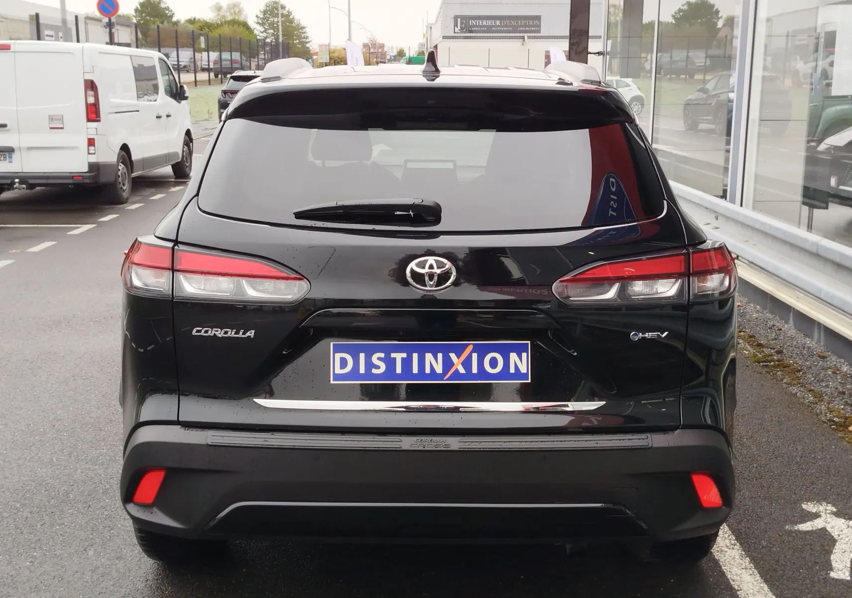 Vue arrière d'une Toyota Corolla Cross Hybrid 140 Luxury Limited noire, avec feux arrière allongés et logo distinctif.