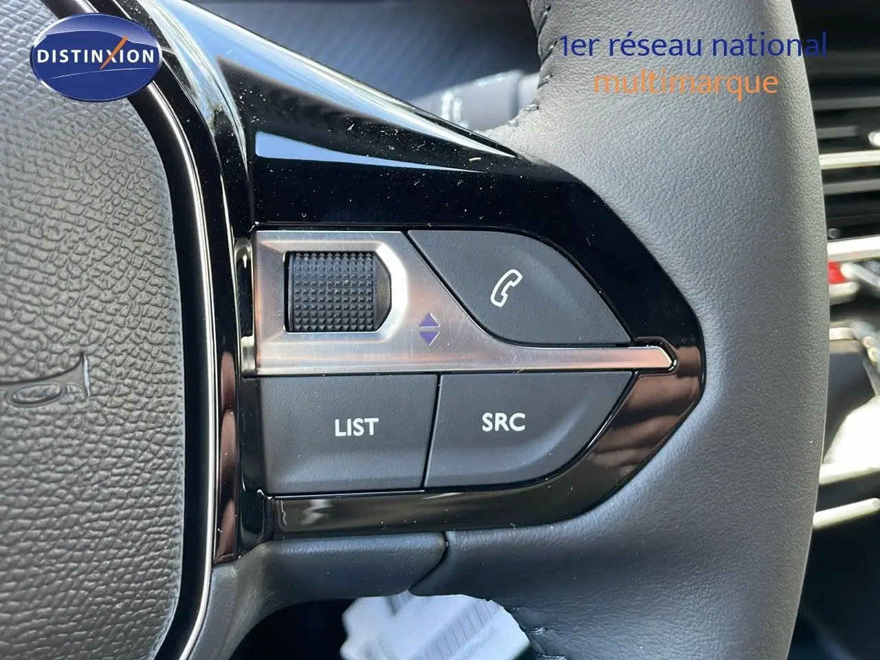 Gros plan sur les commandes du volant en cuir gris du Peugeot 2008 2025 finition Allure, boutons audio et téléphone visibles.