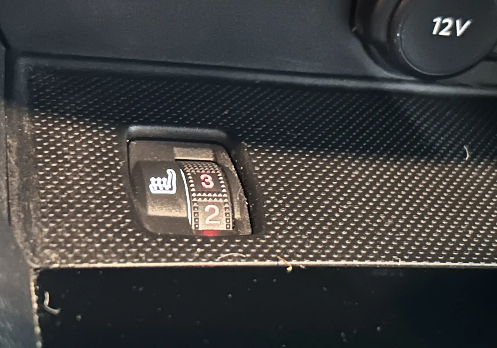 Gros plan sur le bouton de réglage de la chauffe siège en position 2, intérieur noir texturé de la Peugeot 308 gris 2021.