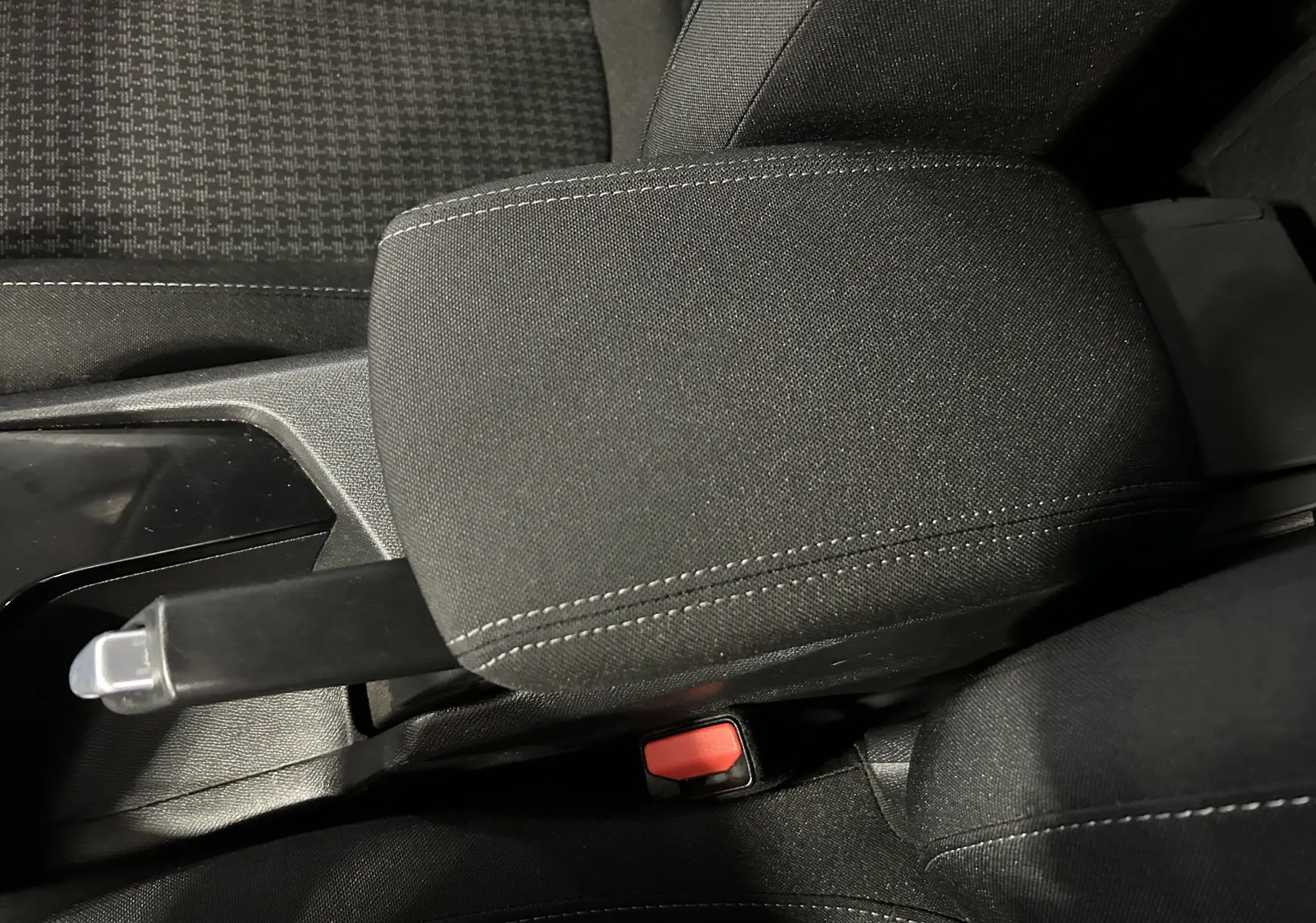 Gros plan sur l'accoudoir central et frein à main manuel d'une Peugeot 308 Active Pack gris, intérieur tissu noir.