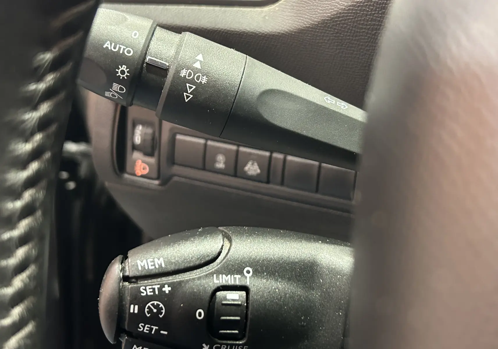 Gros plan sur les commandes de régulateur et feux d'une Peugeot 308 Active Pack gris, intérieur noir.