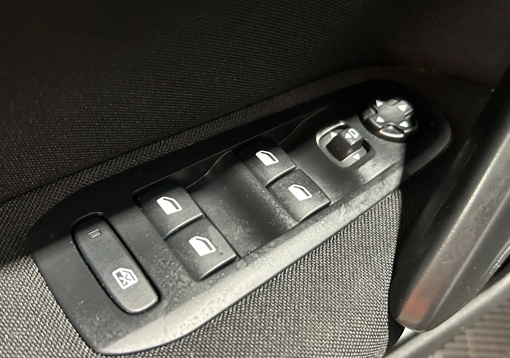 Gros plan sur les commandes de lève-vitres et réglage des rétroviseurs côté conducteur d'une Peugeot 308 gris 2021.
