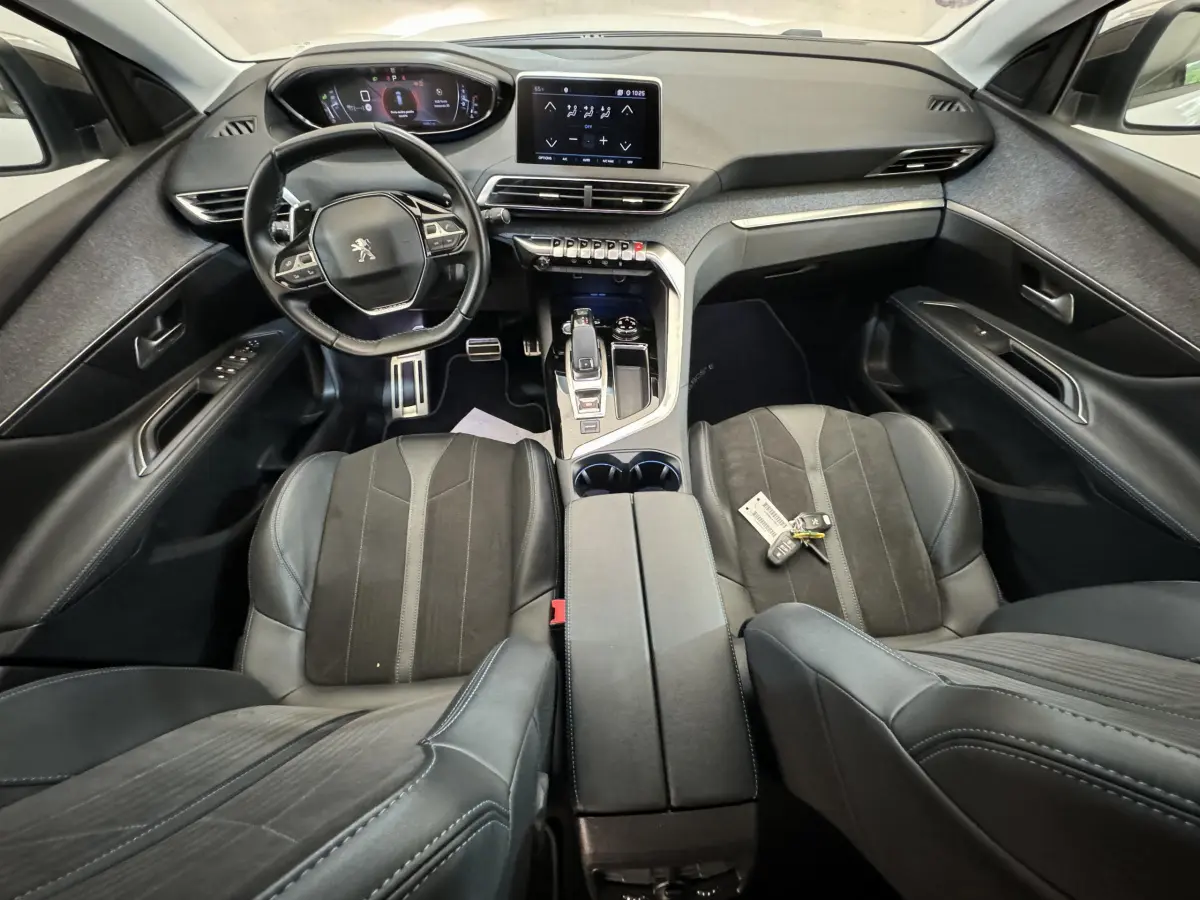 Intérieur noir du Peugeot 3008 2019 vu de dessus, avec volant cuir, console centrale et clés sur siège passager.