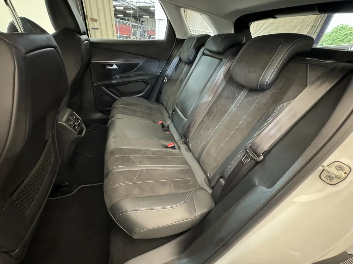 Vue côté droit des sièges arrière en cuir noir et alcantara du Peugeot 3008 blanc, avec ceinture de sécurité et appuie-têtes visibles.