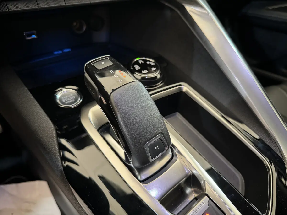 Le levier de vitesse automatique noir et cuir du Peugeot 3008 blanc, vu en gros plan intérieur central.