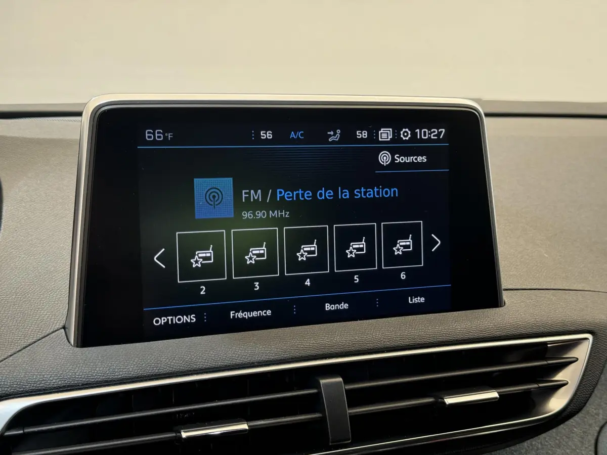 Écran tactile central affichant la radio FM dans l'habitacle du Peugeot 3008 blanc, vue rapprochée du tableau de bord.