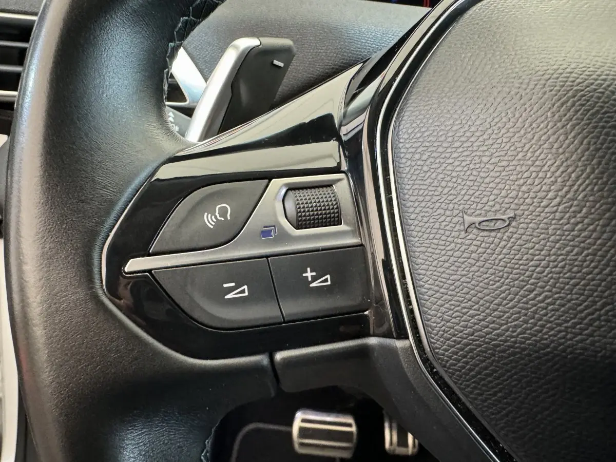 Gros plan sur les commandes gauche du volant cuir noir du Peugeot 3008 blanc, version Crossway 2019.