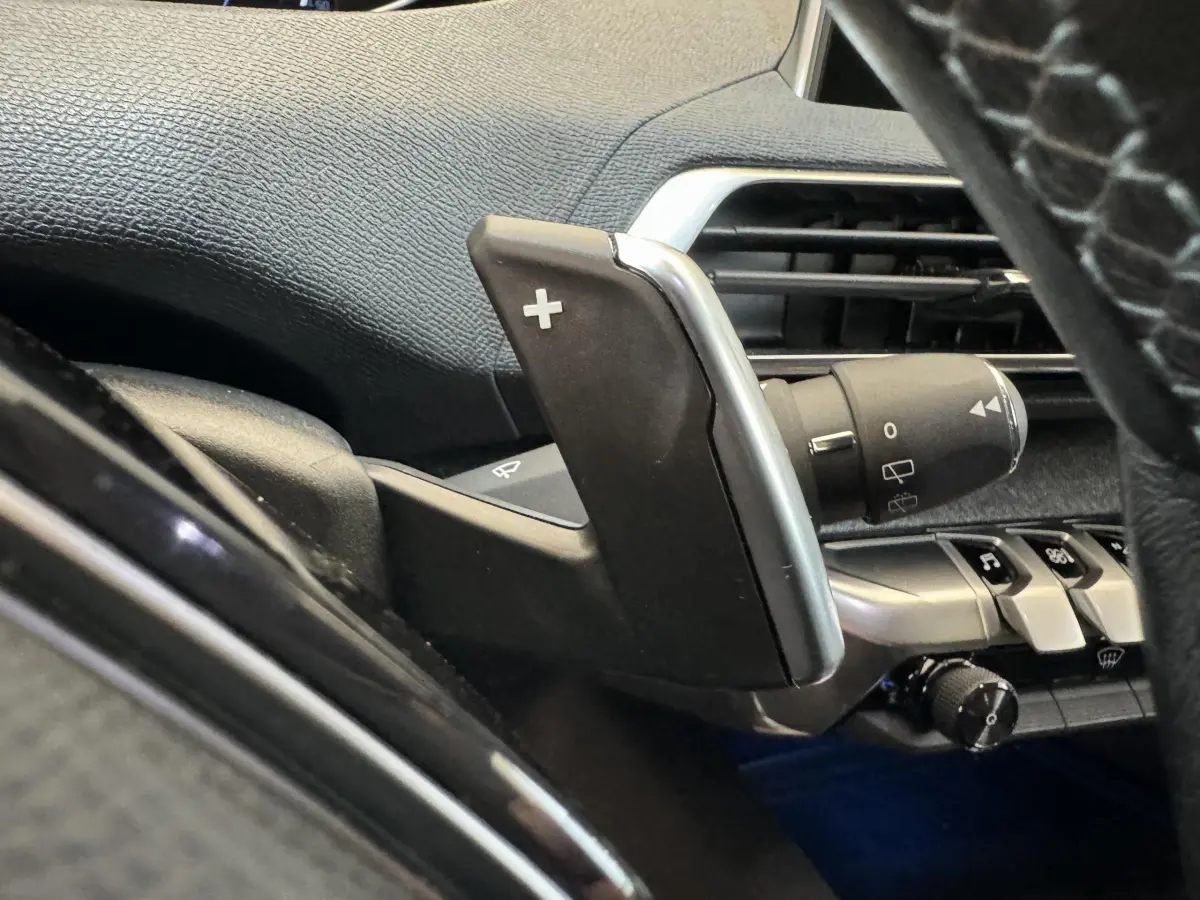 Gros plan sur la palette de changement de vitesse droite noire et argentée dans le tableau de bord intérieur du Peugeot 3008 blanc.