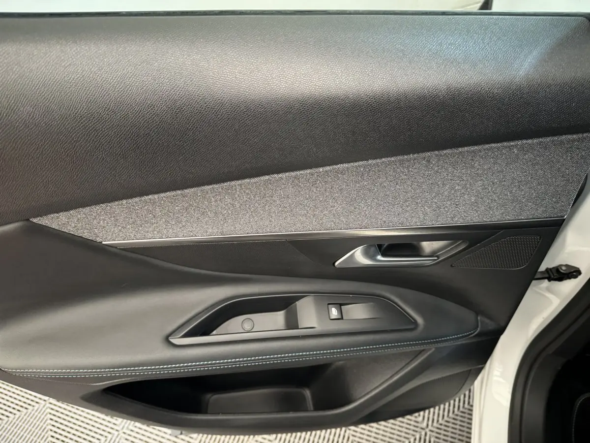 Gros plan sur la porte avant droite blanche du Peugeot 3008 avec garniture noire et surpiqûres bleues.
