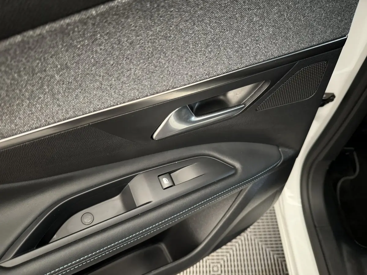 Gros plan sur la porte avant gauche blanche du Peugeot 3008 2019, avec garniture noire et surpiqûres bleues.