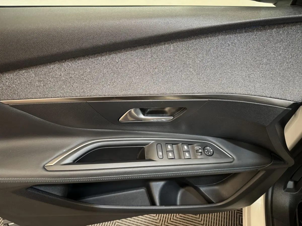 Gros plan sur la porte côté conducteur du Peugeot 3008 blanc, montrant les commandes des vitres et le revêtement noir.