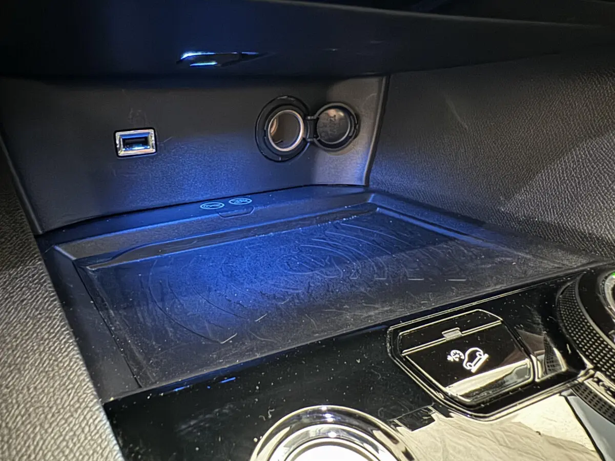 Gros plan sur la console centrale noire du Peugeot 3008 blanc, montrant prise USB, allume-cigare et commande de descente assistée