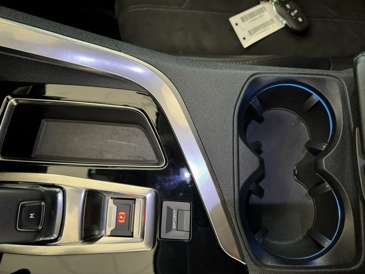 Gros plan sur la console centrale noire du Peugeot 3008 avec bouton Sport et frein à main électrique allumé.