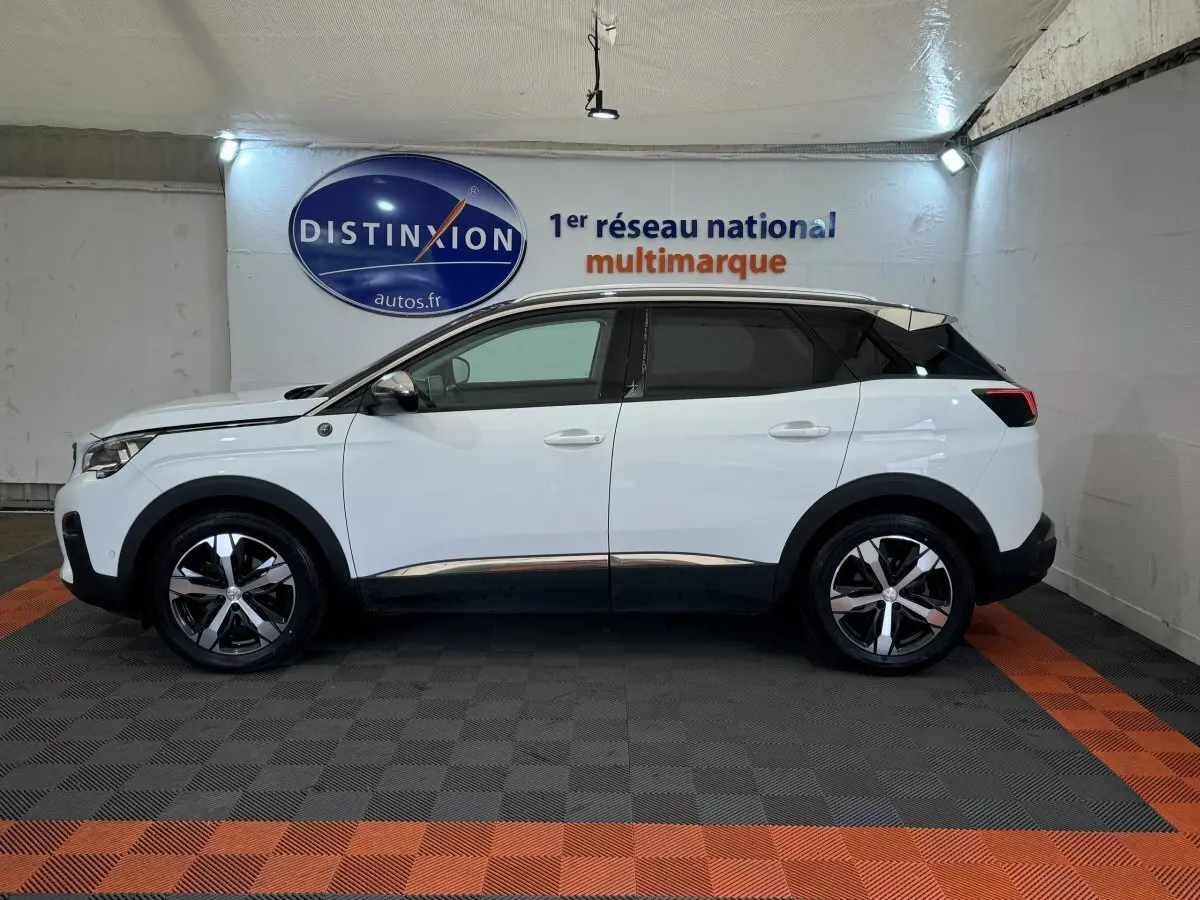 Profil droit d'un Peugeot 3008 blanc avec toit noir et jantes alliage bicolores dans un showroom.