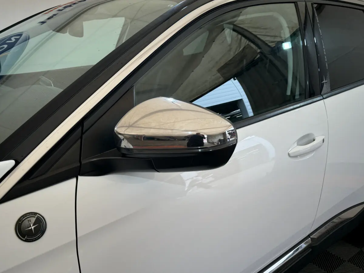 Gros plan sur le rétroviseur chromé côté gauche d'un Peugeot 3008 blanc avec logo spécifique sur la portière.