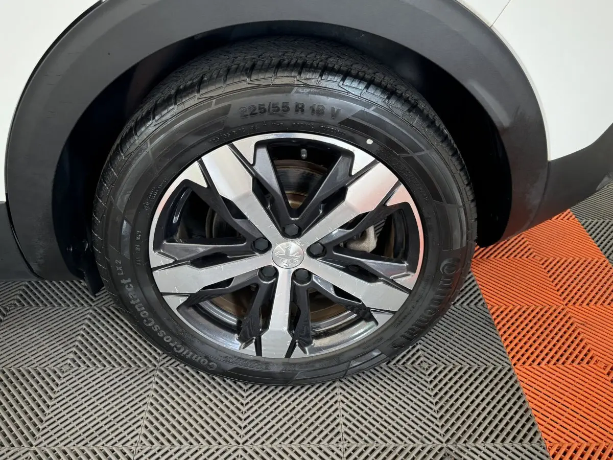 Gros plan sur la roue avant gauche du Peugeot 3008 blanc, mettant en valeur la jante alliage au design moderne.