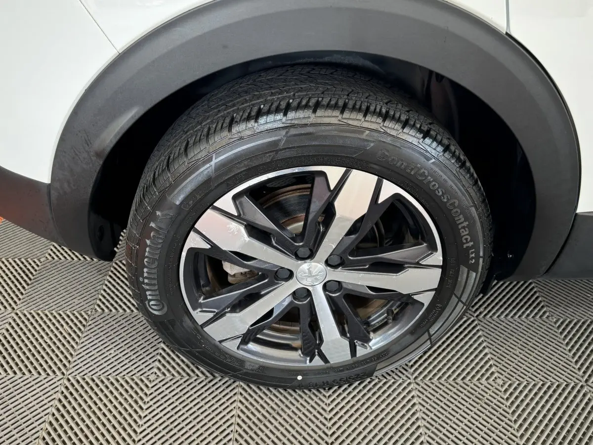 Gros plan sur la roue avant droite du Peugeot 3008 blanc, mettant en valeur la jante alliage bicolore et le pneu Continental.