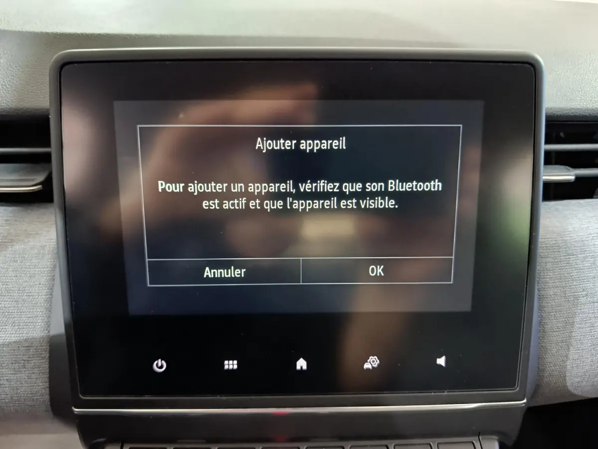 Écran tactile central de la Renault Clio gris foncé affichant un message d'ajout d'appareil Bluetooth.