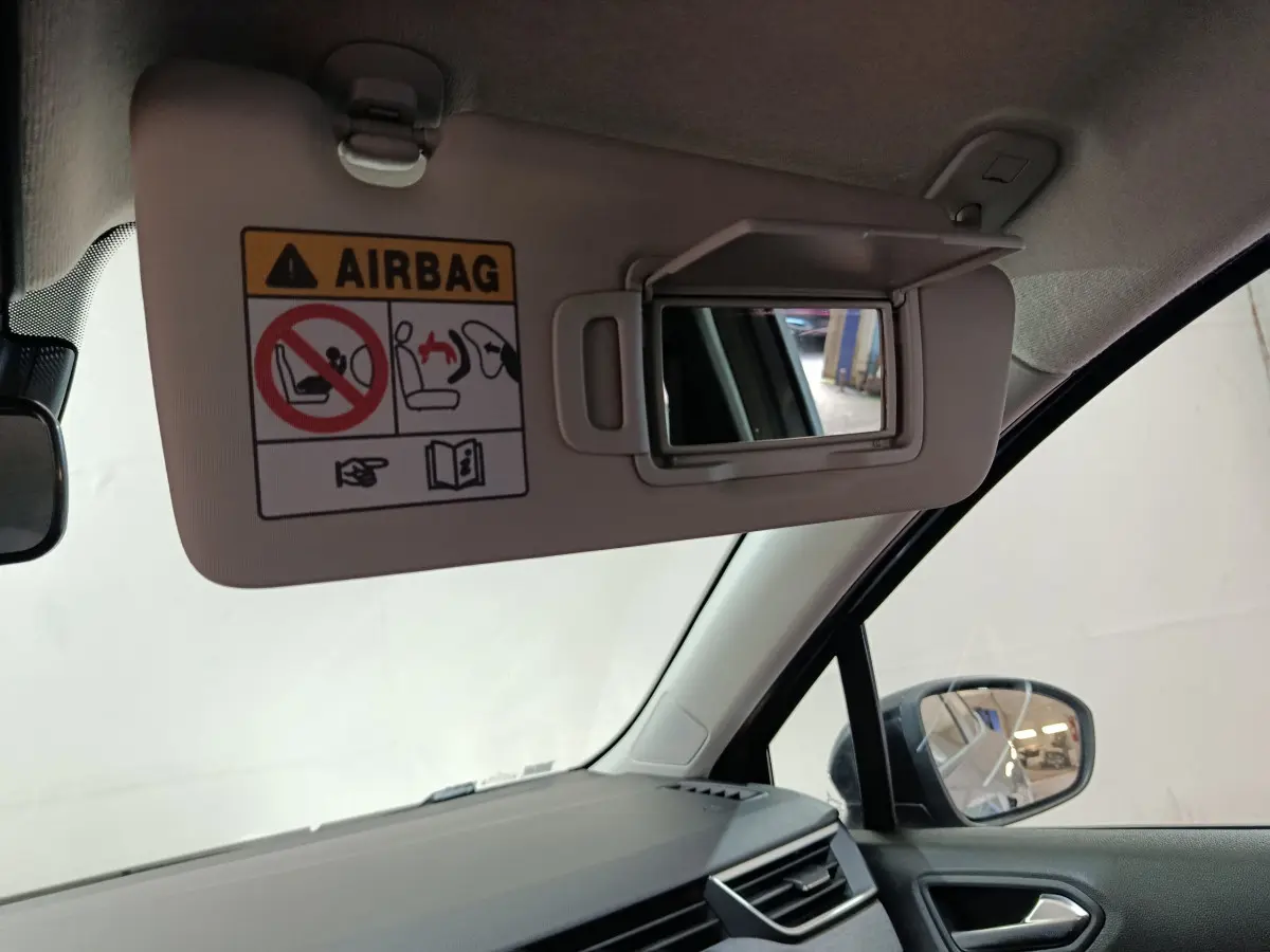 Détail du pare-soleil côté conducteur avec miroir intégré et avertissement airbag dans une Renault Clio gris foncé 2025.