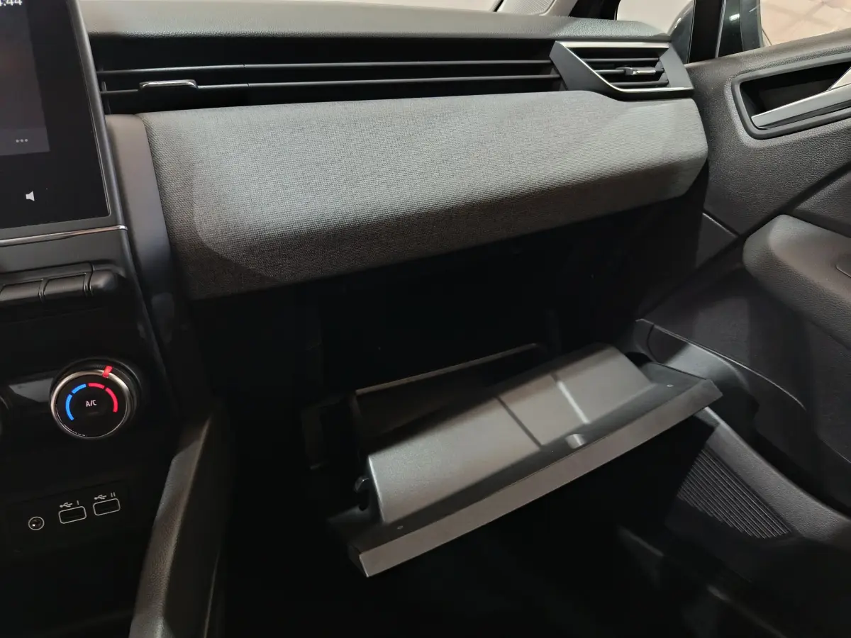 Intérieur de la Renault Clio Evolution Blue dCi 100 2025, vue côté passager sur la boîte à gants ouverte et commandes climatisation.