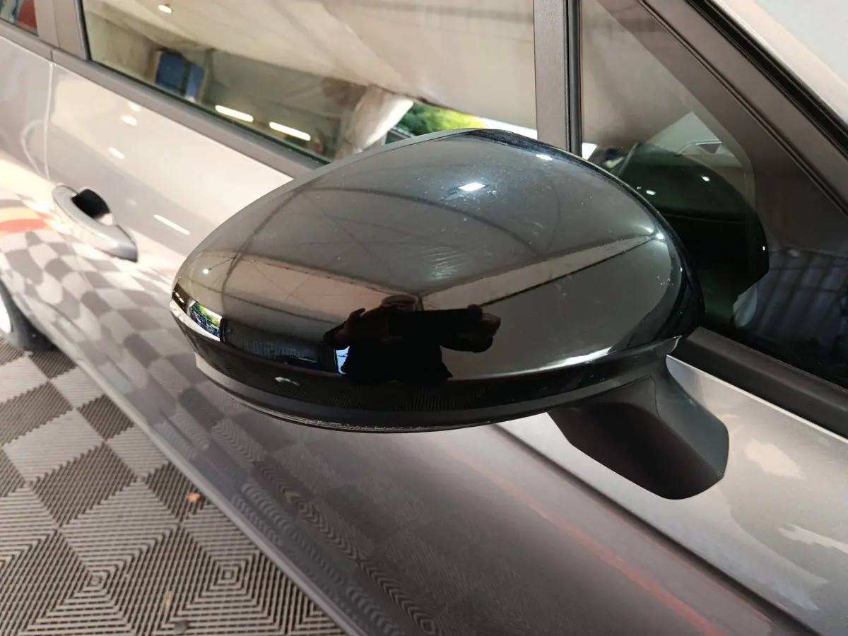 Rétroviseur côté gauche noir brillant sur Renault Clio gris foncé, vue rapprochée du côté conducteur.