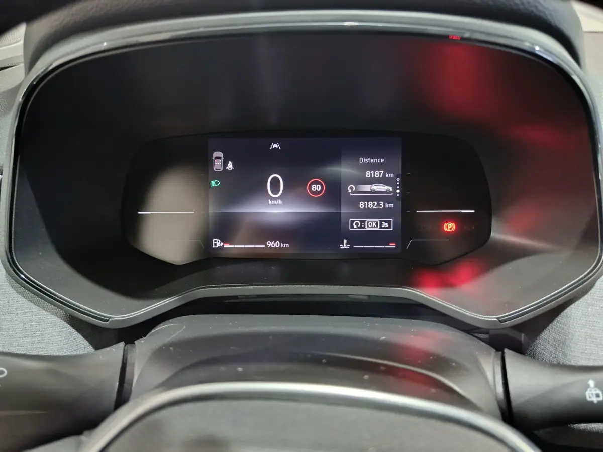 Tableau de bord numérique de la Renault Clio gris foncé 2025 affichant la vitesse, autonomie et alertes au centre du combiné d'instruments.