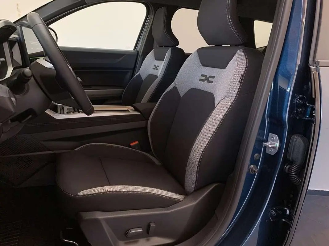Vue intérieure côté conducteur du Dacia Bigster Hybrid 155 Journey Plus 2026, sièges tissu noir et gris avec logo X brodé.