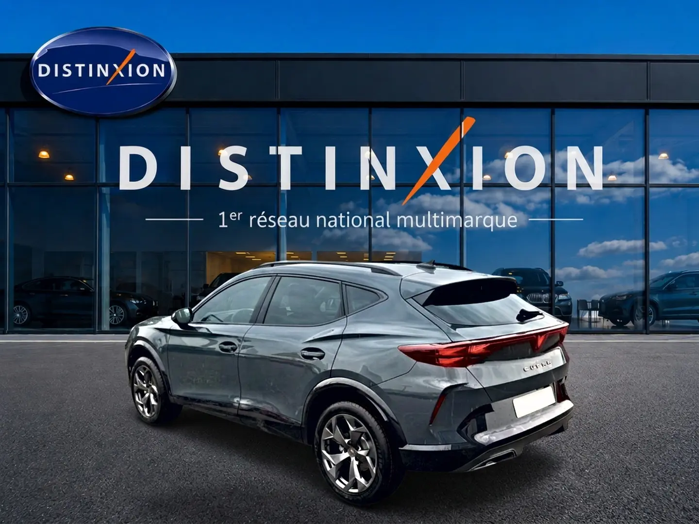 Vue 3/4 arrière droite d'un CUPRA Formentor gris métallisé garé devant une vitrine Distinxion.